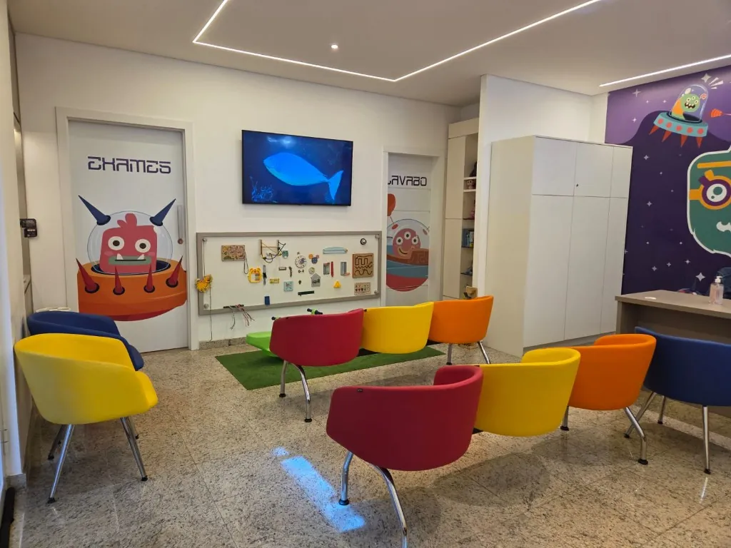 Sala de espera da Oftalmokids com cadeiras coloridas e porta de exames